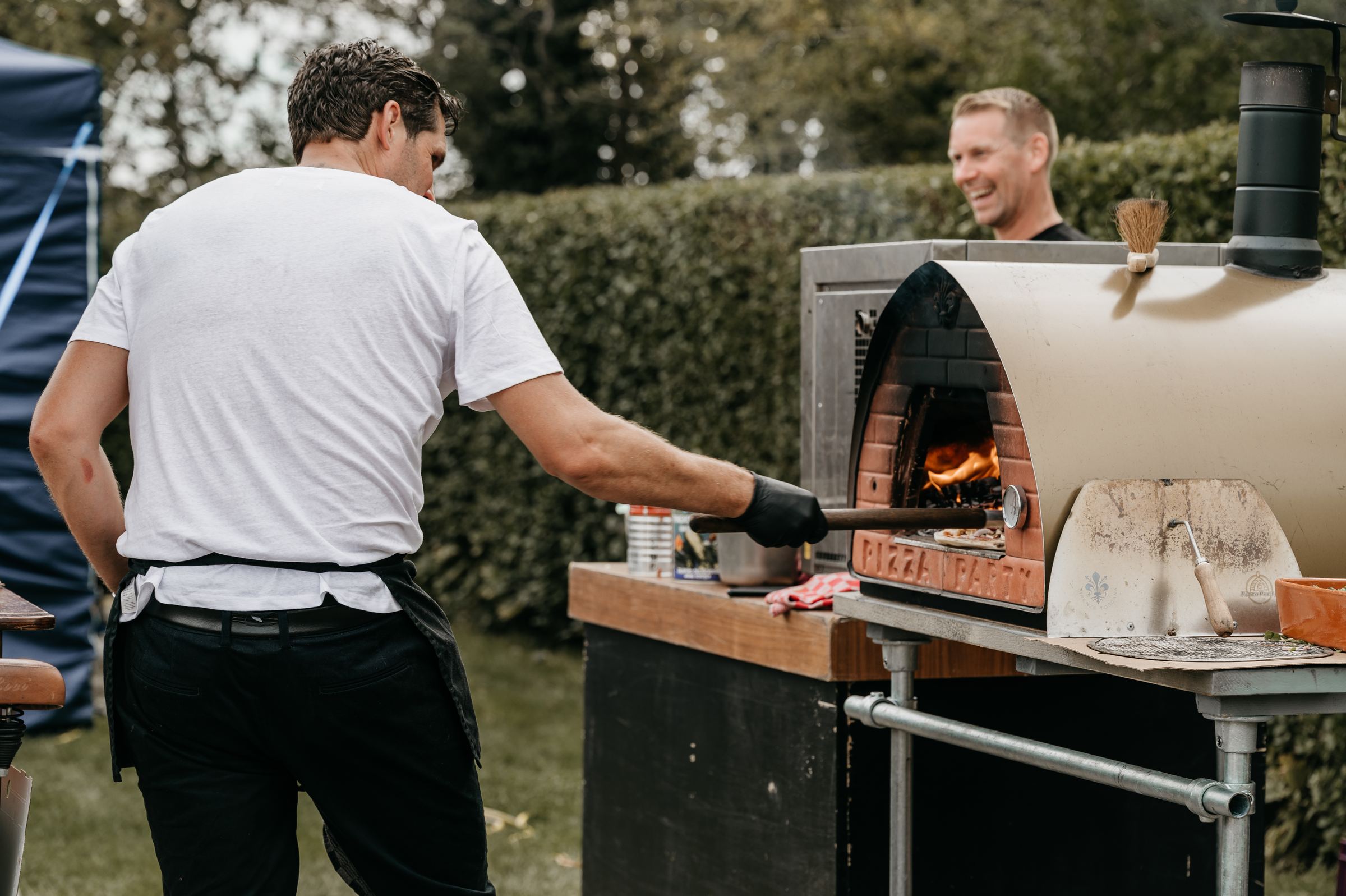 De pizzabakker schuift een pizza de houtoven in